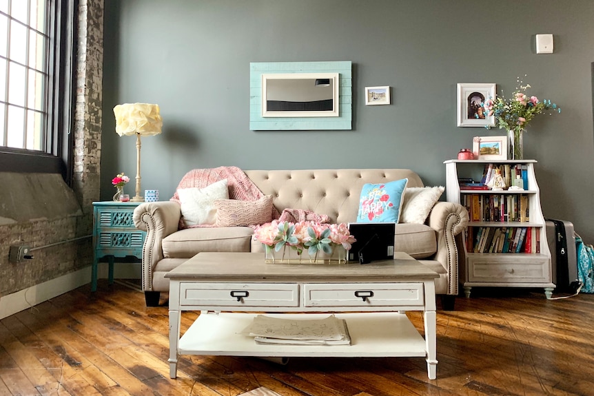 A living room with a beige couch and accents of light blue and pink around it.