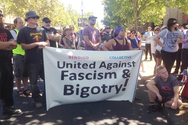 The Bendigo Action Collective hold up a banner reading "united against fascism and bigotry"