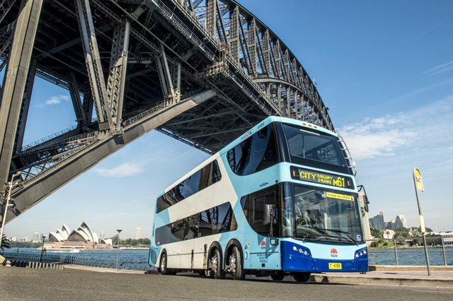 A double-decker bus parked under the Sydney Harbour Bridge.
