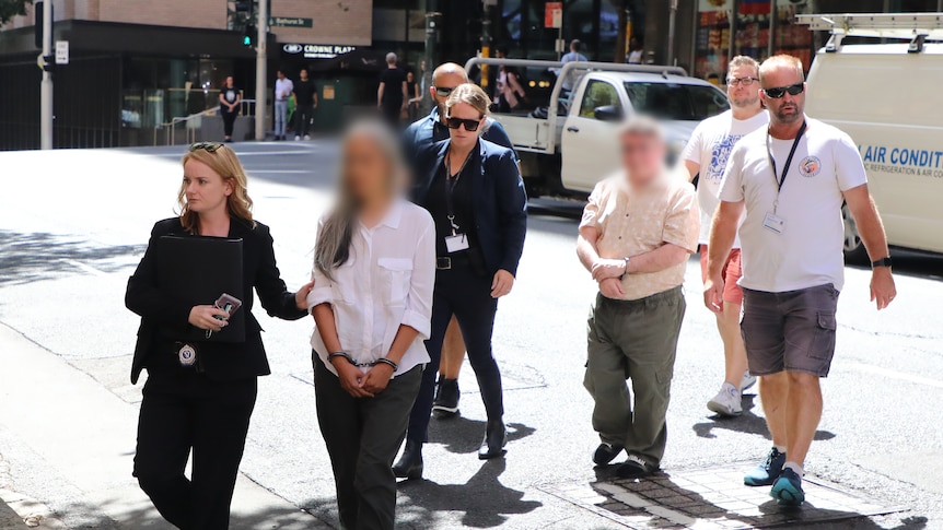 Police walking two people off with their faces blurred