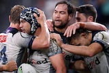 Six Melbourne Storm NRL players embrace as they celebrate a try against Wests Tigers.