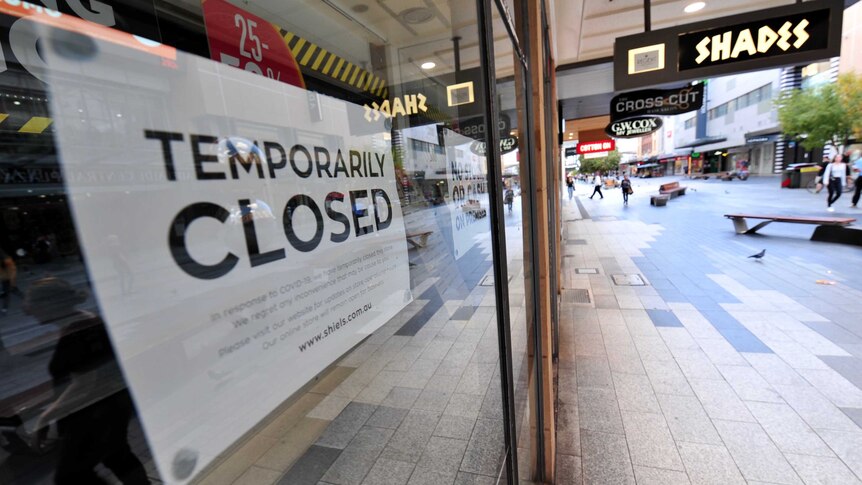 A white sign in a business window with the words 'temporarily closed'