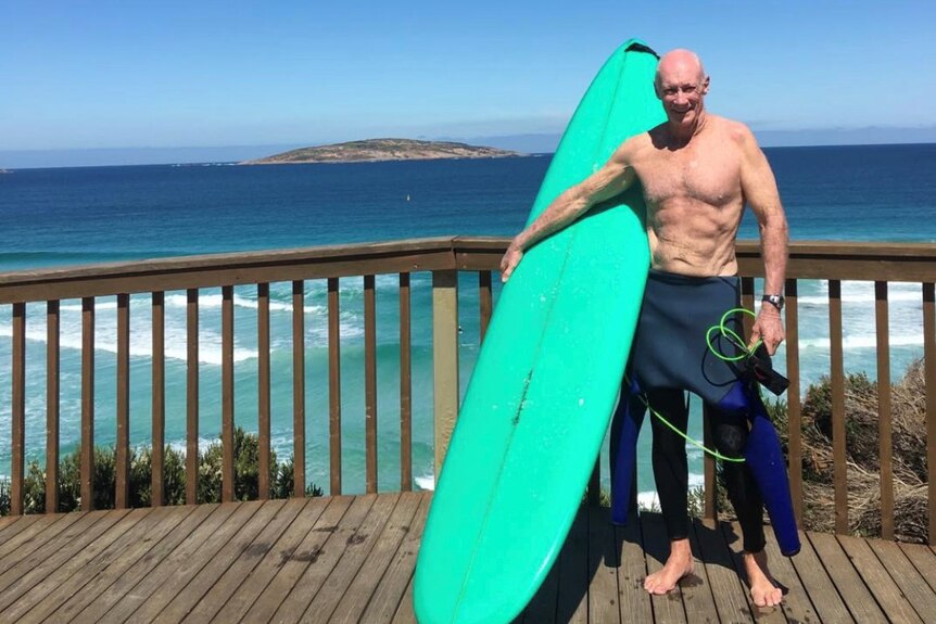 Des Salmon standing with his surfboard at Esperance in Western Australia.