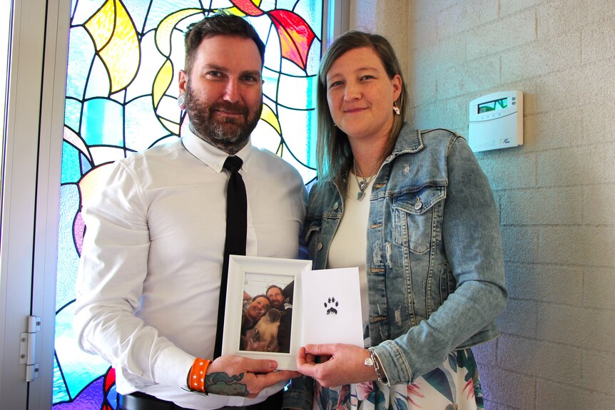Man and woman in church with photo of their Siamese cat who died aged 18 