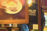 Image of a dome coffee cup in the foreground with a police officer in the background examining scene at cafe.