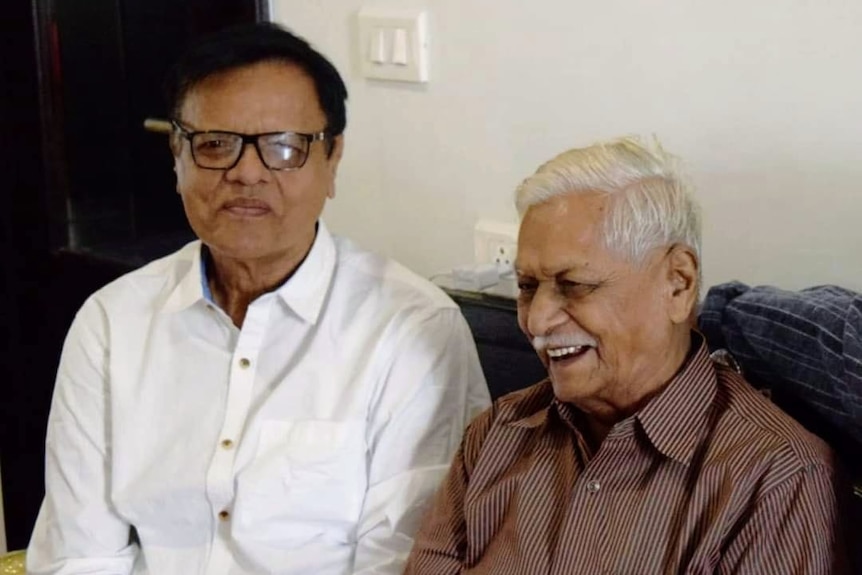 Kailash Tiwari's father and father-in-law sit together on a couch smiling. 