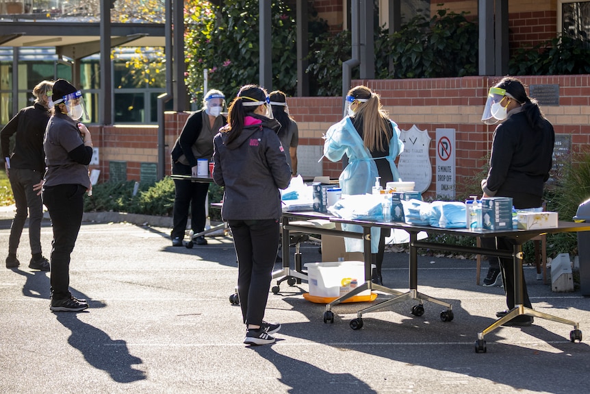 Health workers prepare to conduct COVID tests in a carpark