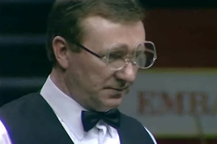 Dennis Taylor stands and looks at the table