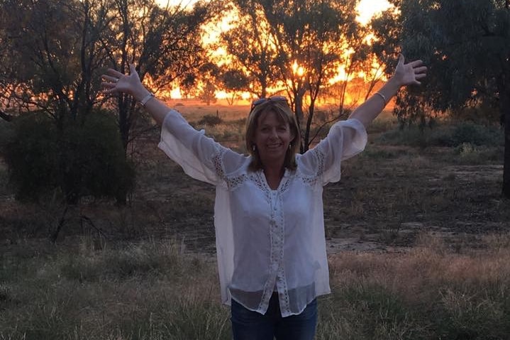 Alison at sunset looking excited with her arms in the air