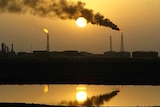 Smoke rises from Iraqi refinery al-Shouayba in Basra at sunset, reflected in an oil field.