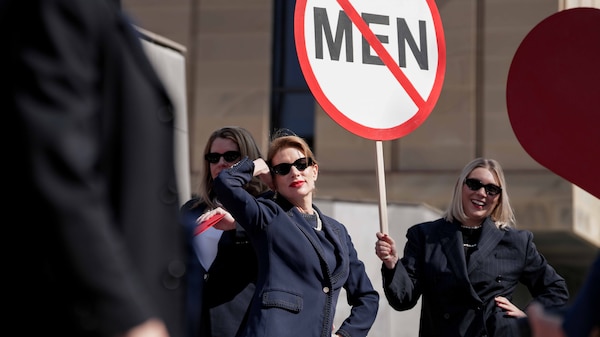 Women in blue suits dance on documents with red signs
