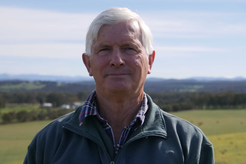 A man in his late 60s or early 70s with white hair looking at the camera.