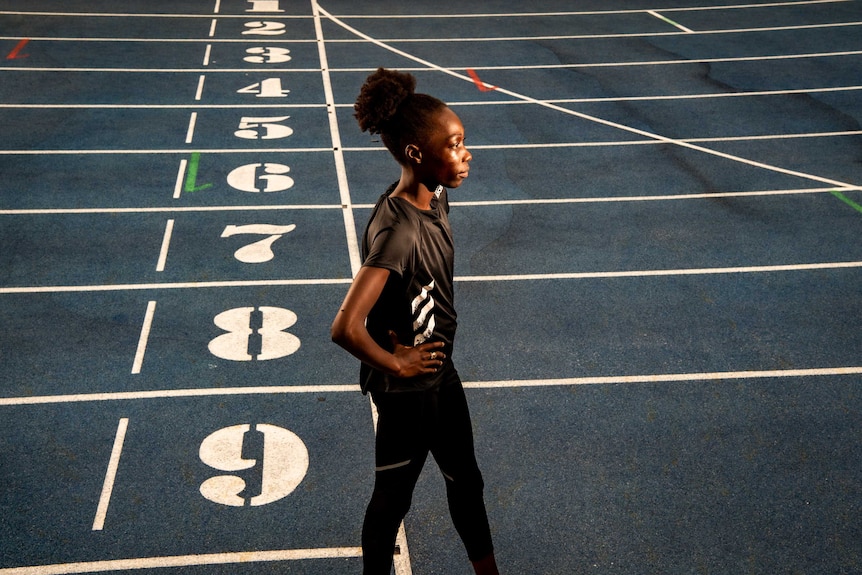 Bendere Oboya walks with her hands on her hips on an athletics track.