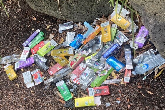 Dozens of empty vape boxes are strewn on the ground with soft drink and alcohol bottles.