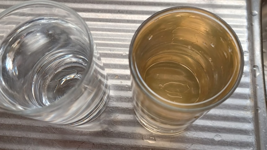 two glasses of water side by side one with brown water and the other with clear water