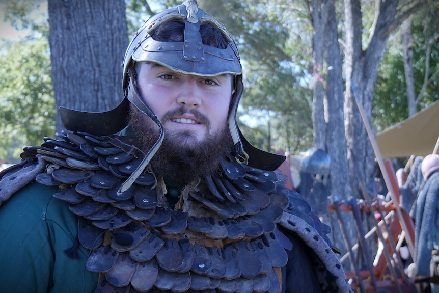 A bearded young man in leather armour and a helmet