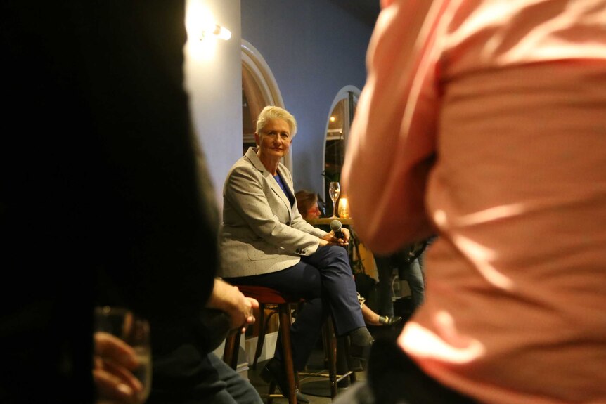 Kerryn Phelps in-between two people, holding a microphone