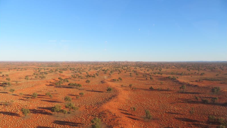 an aerial photo of a house and sheds on red dirt.
