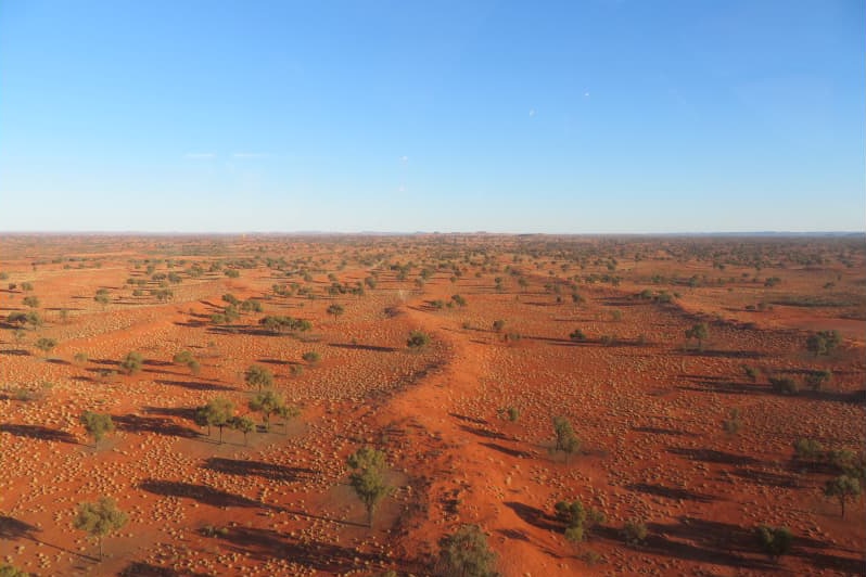 an aerial photo of a house and sheds on red dirt.