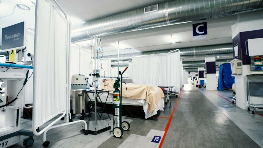 A patient in a hospital bed set up in a carpark