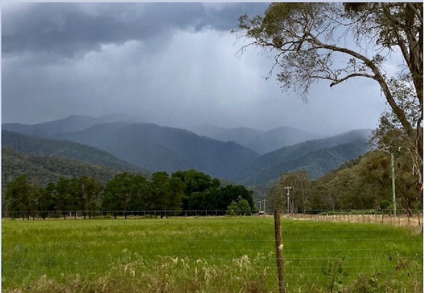 Green pastures roll into misty grey mountains. 