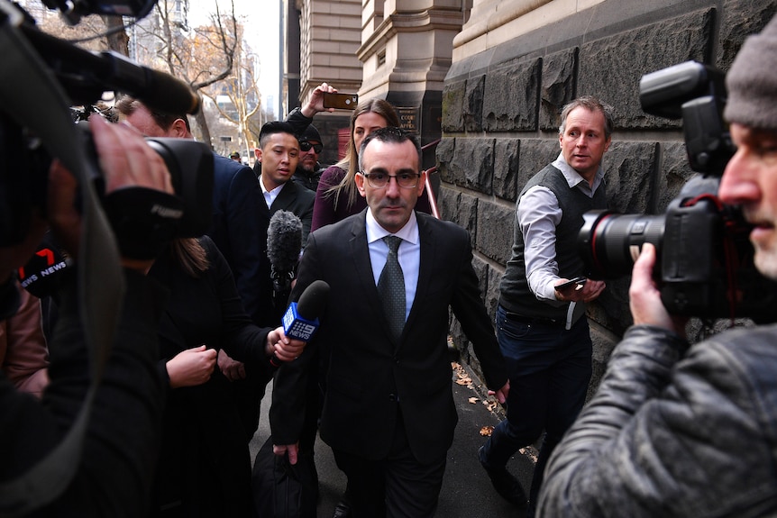 A man surrounded by reporters.