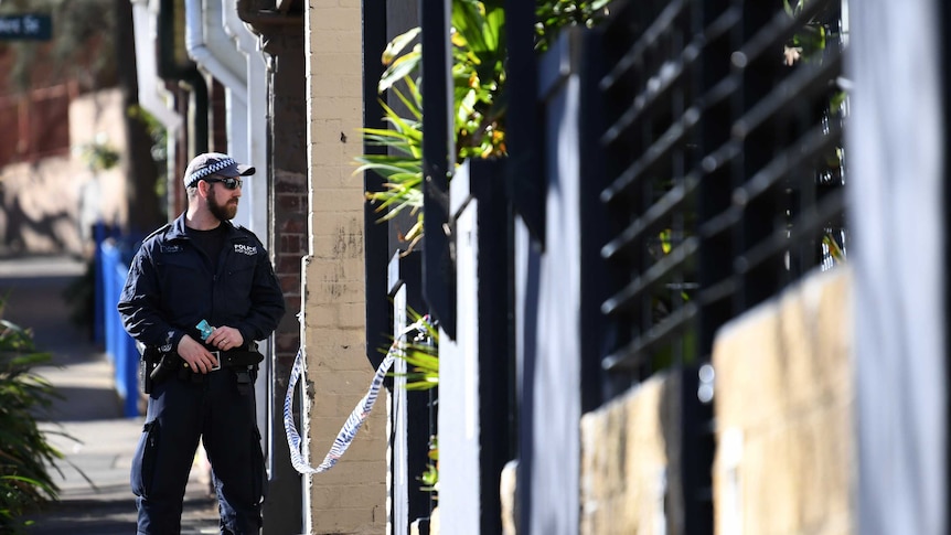 A New South Wales policeman stands guard at the back of of a property in Surry Hills in Sydney.