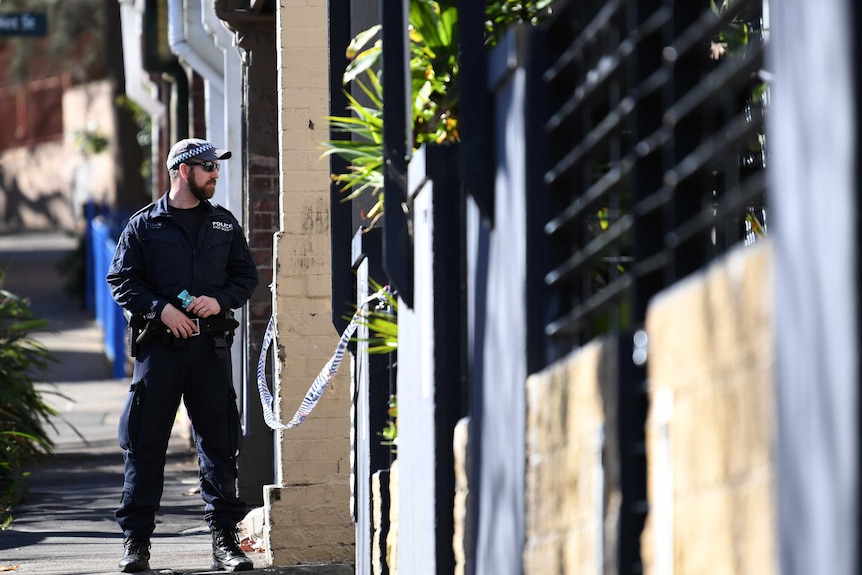 A New South Wales policeman stands guard at the back of of a property in Surry Hills in Sydney.