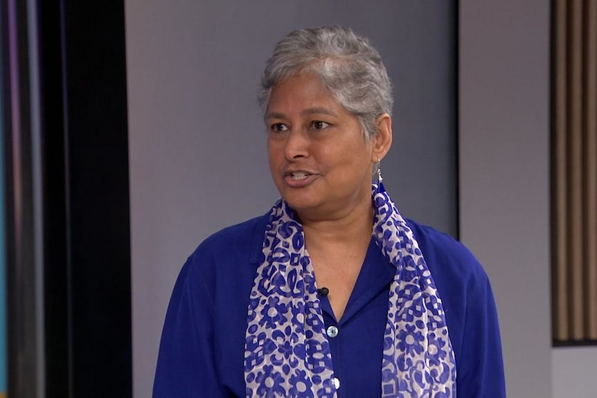 An older woman of east asian decent with grey hair in a purple shirt 