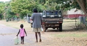 A man and a little girl walking along a road in Oombulgurri before settlement demolished