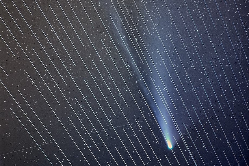 Une photo d'étoiles avec des stries de satellites.