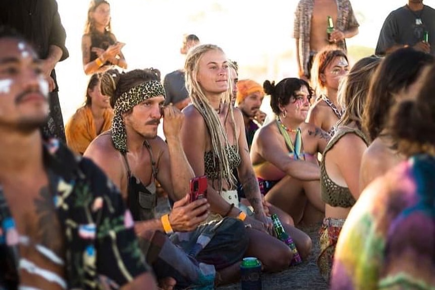 Party goers in colourful outfits and face paint gather on a property in Margaret River 