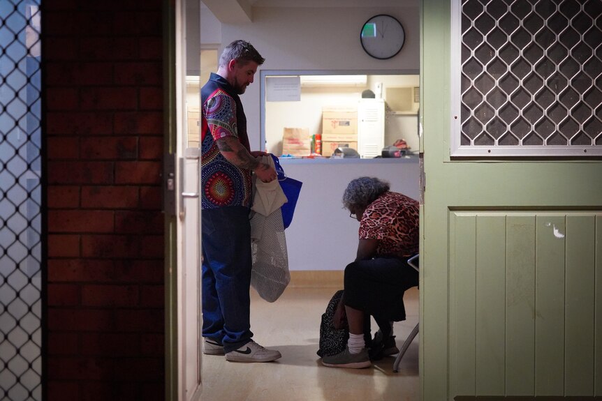 A man and a woman inside a sobering-up shelter, framed by a doorway. 