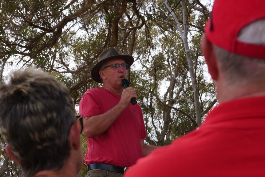 A man with a red shirt on speaks with a microphone.