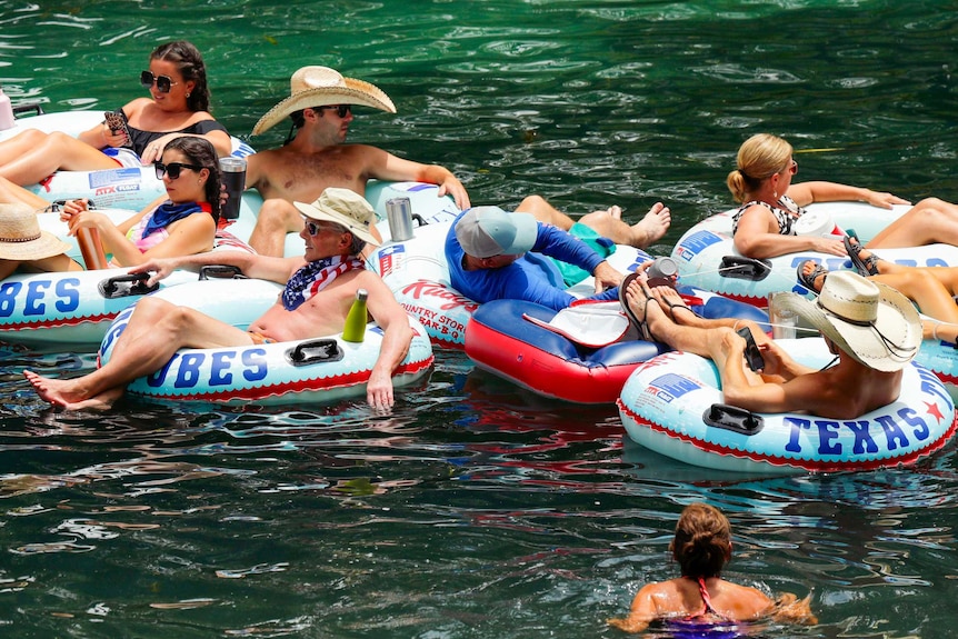 A group of people floating on large rubber tubes in water