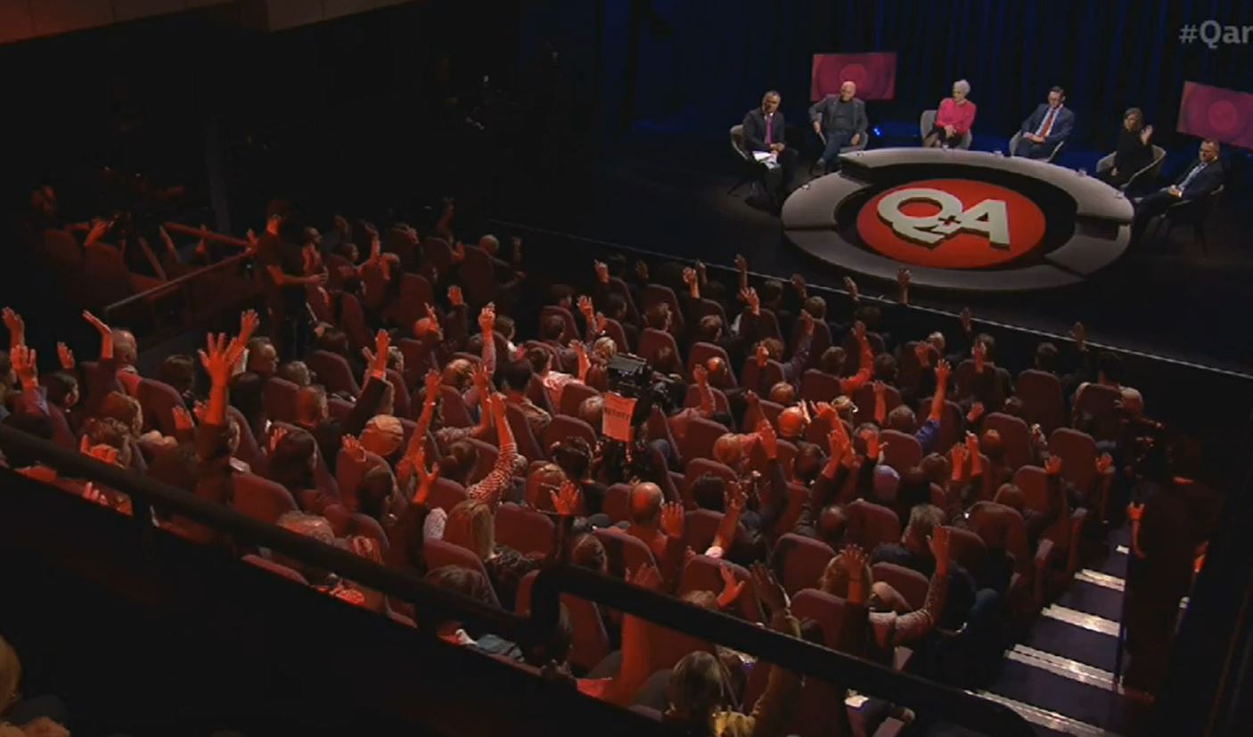 Audience members on the Q+A set raise their hands