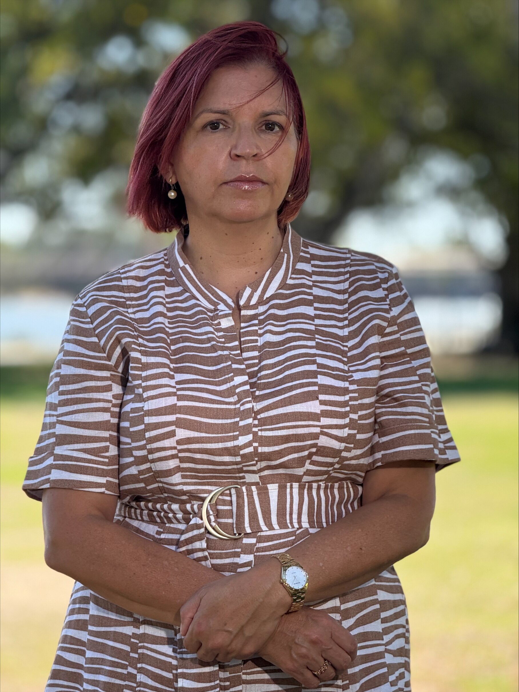 A woman with red hair wears a stiped top 