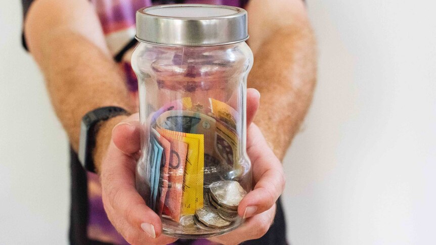 Man holding out jar of Australian cash