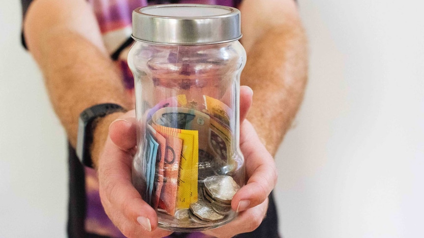 Man holding out jar of Australian cash