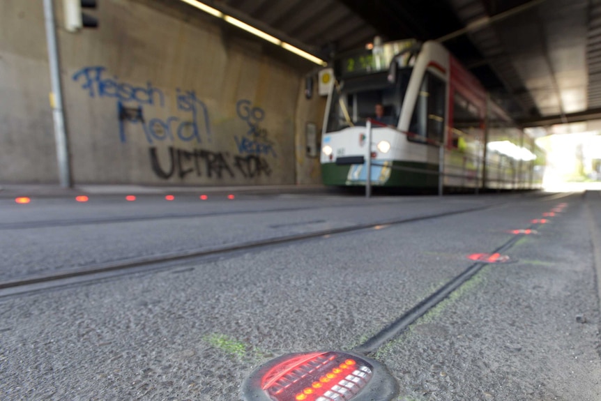 Red lights in the ground in front of a tram.