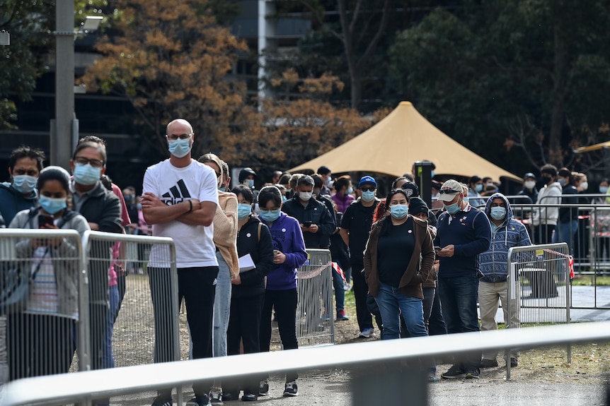 People wearing masks queue for a vaccination