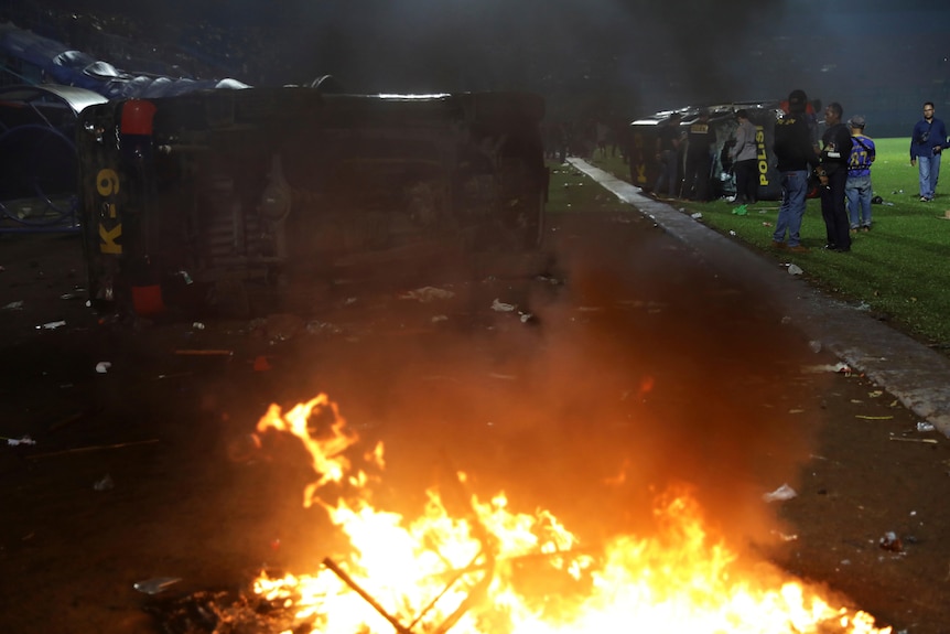 Plain-clothed officers stand near the wreckage of police vehicle.