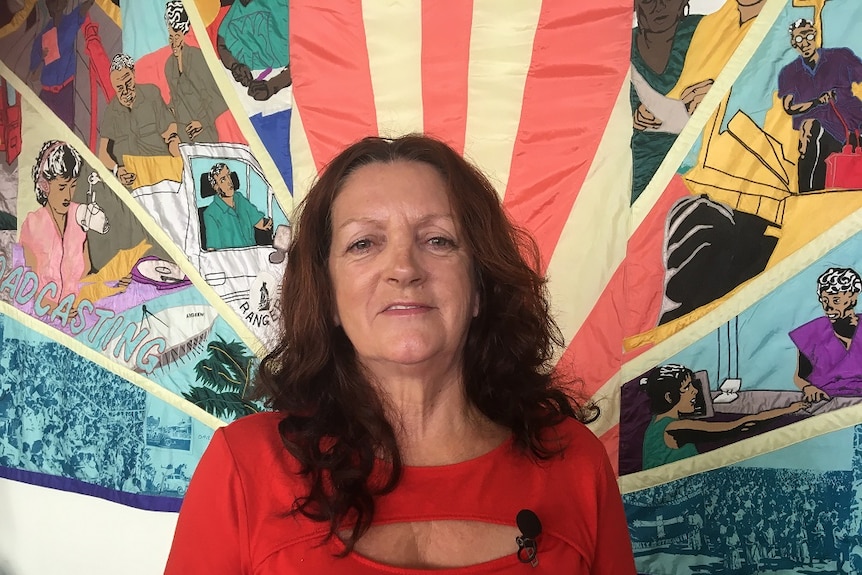 Kay Densley from the CPSU stands in front of a banner in Darwin.