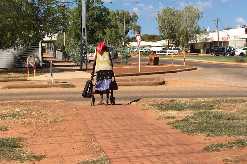 A woman walking in a streets using a walking frame.
