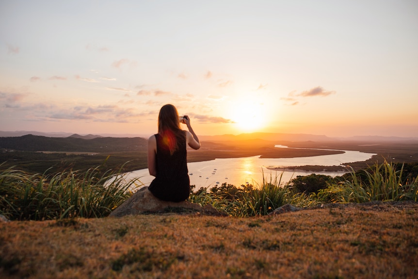 A woman watches a sunset from a mountaintop
