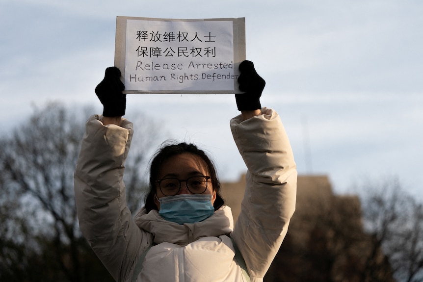 一名戴眼镜的女孩举着一块牌子 上门写着呼吁释放被捕人士
