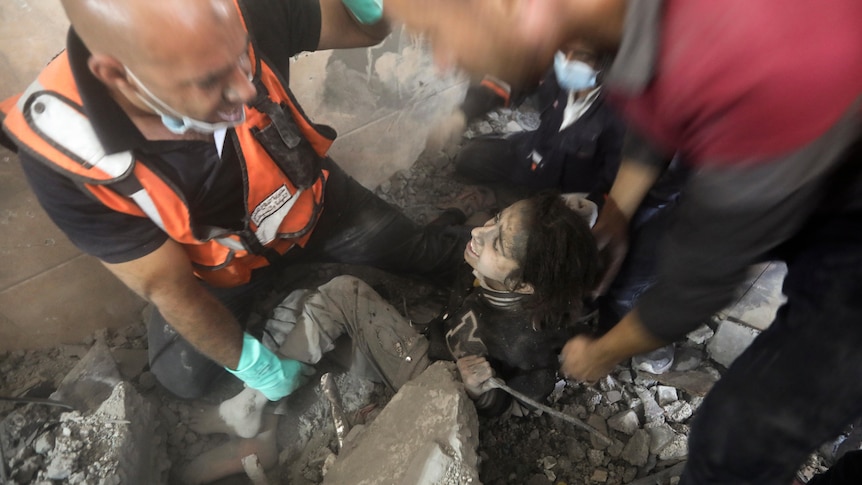 Palestinians rescue a wounded girl from under the rubble of a destroyed building following an Israeli airstrike.