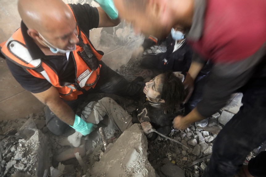 Palestinians rescue a wounded girl from under the rubble of a destroyed building following an Israeli airstrike.