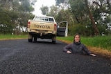 Woman stands in sinkhole on road