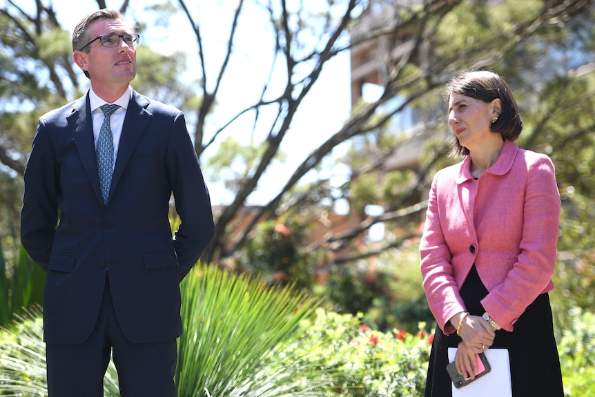 a man wearing glasses standing next to a woman, both are outdoors at a press confrence